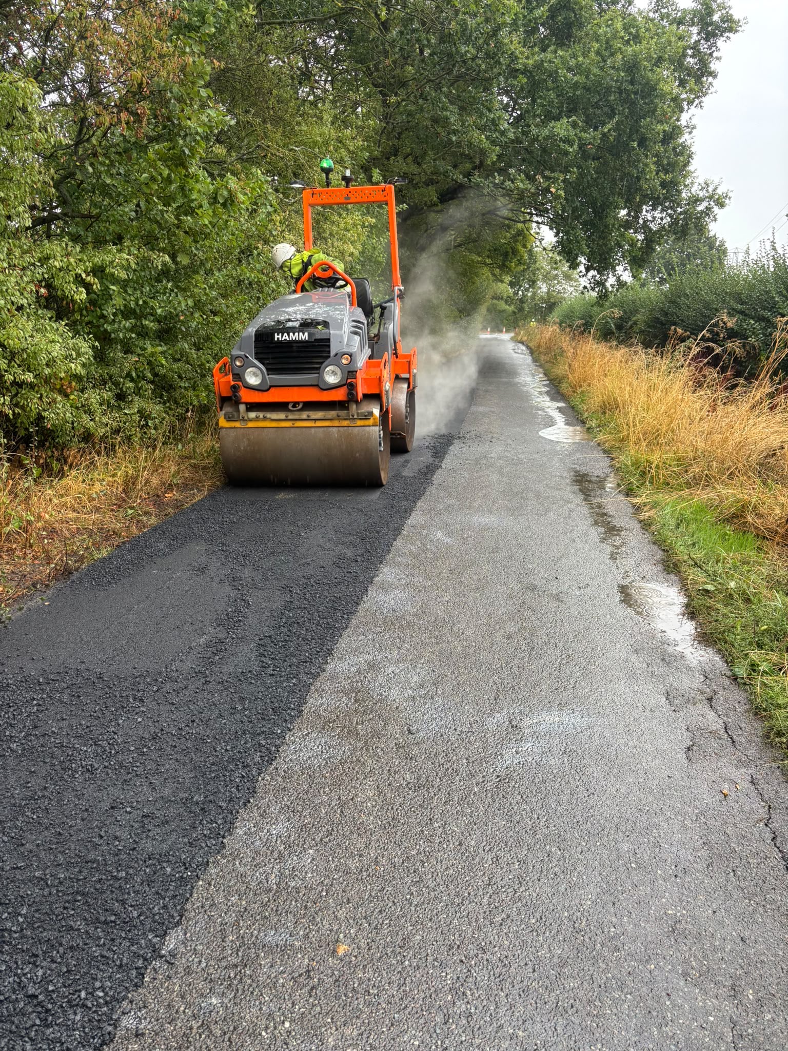Road roller compacting fresh asphalt on a rural road
